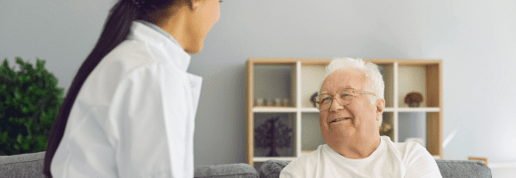 Doctora conversando con adulto mayor durante consulta medica en casa